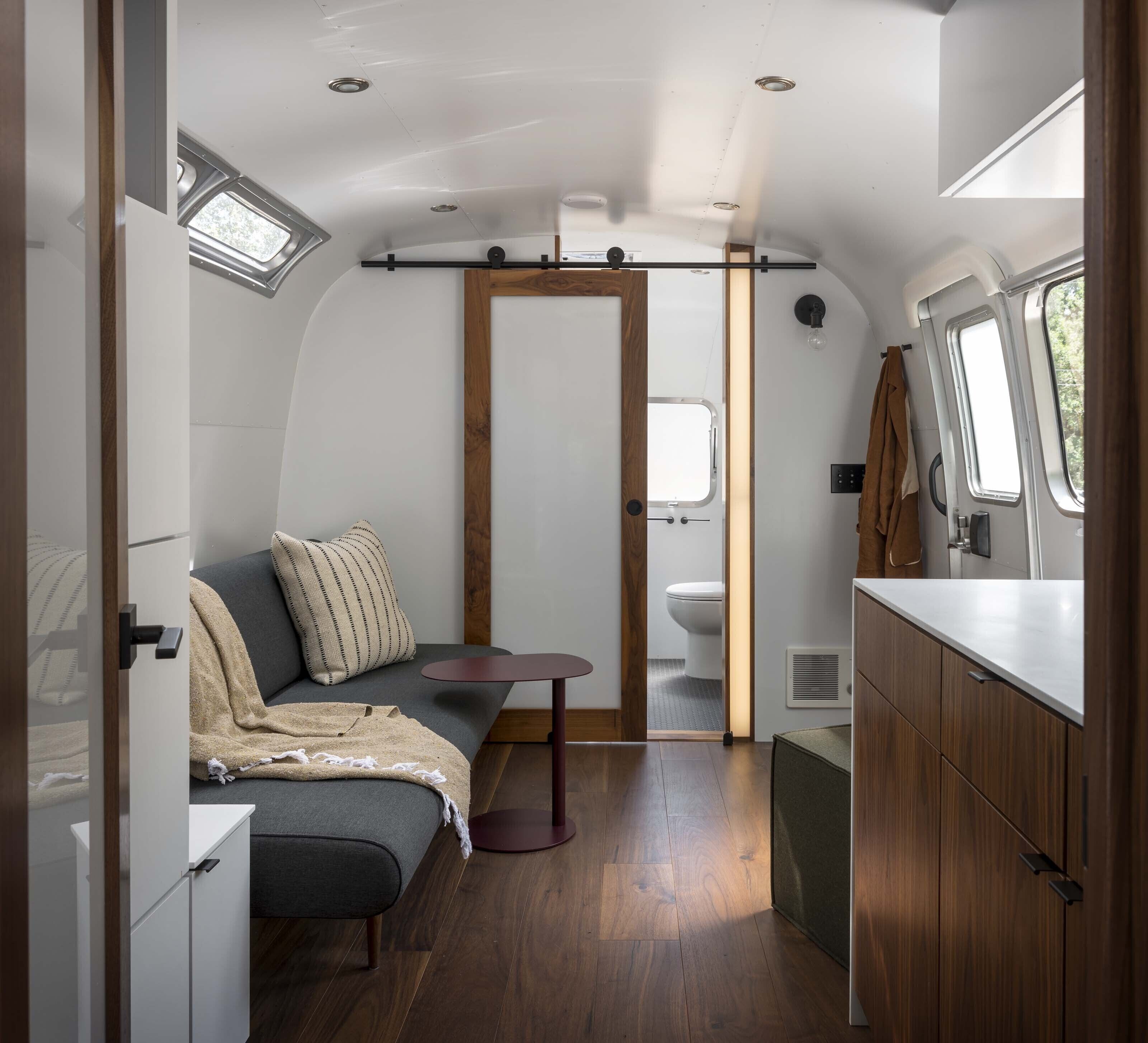 A compact, well-lit interior with a seating area, kitchenette, and a small bathroom.