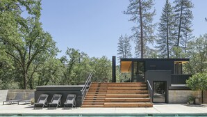 A modern house with a pool, wooden steps, and a view of tall trees. - AutoCamp Yosemite (Mariposa)