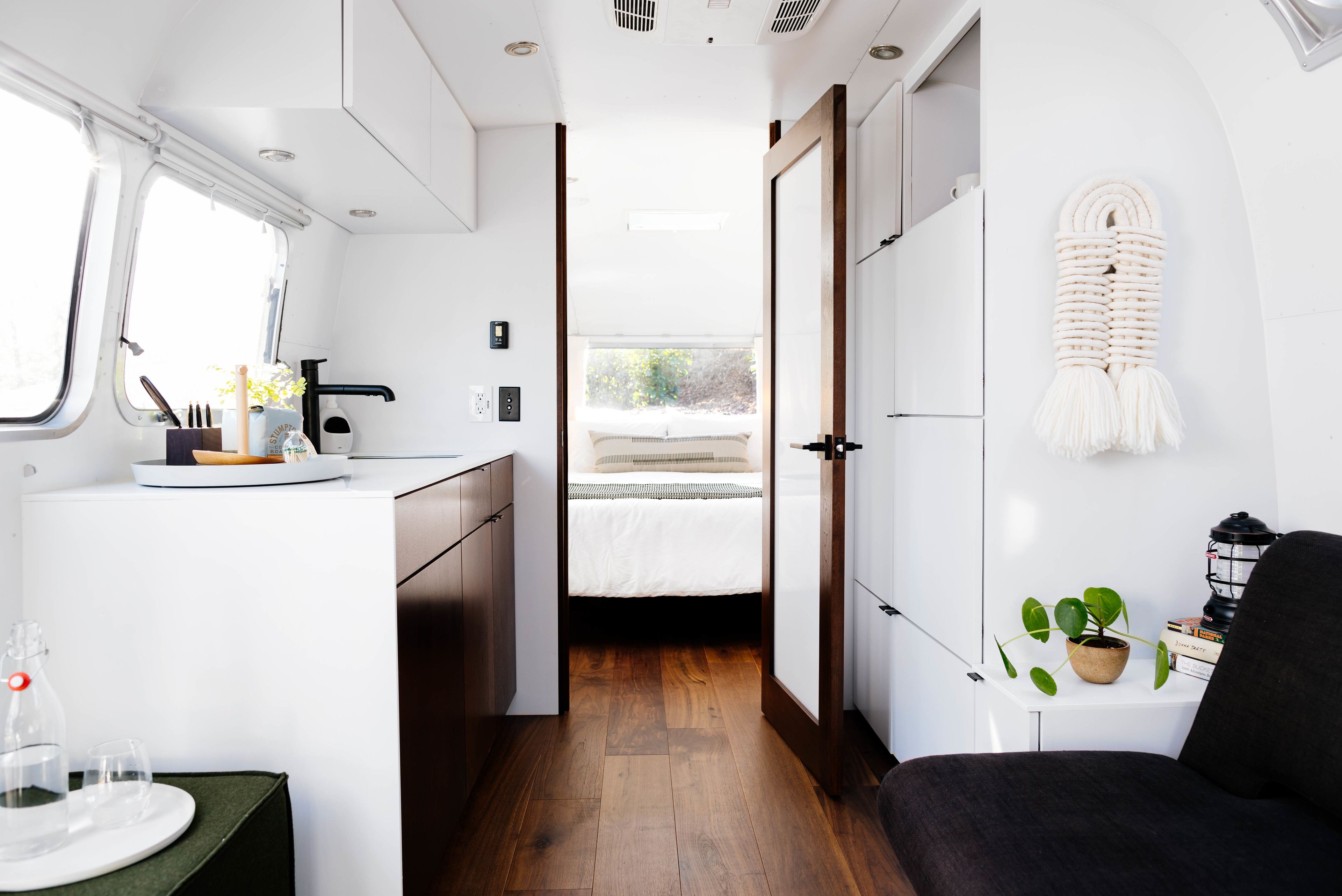 Un espacio interior compacto y bien iluminado, con kitchenette, cama y zona de estar.