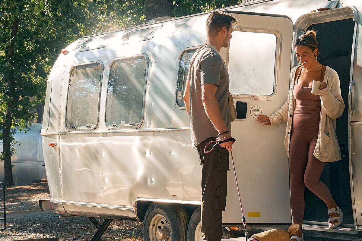 Un camping-car d’époque doté d’une porte coulissante, d’une petite fenêtre et d’un panneau latéral en métal.