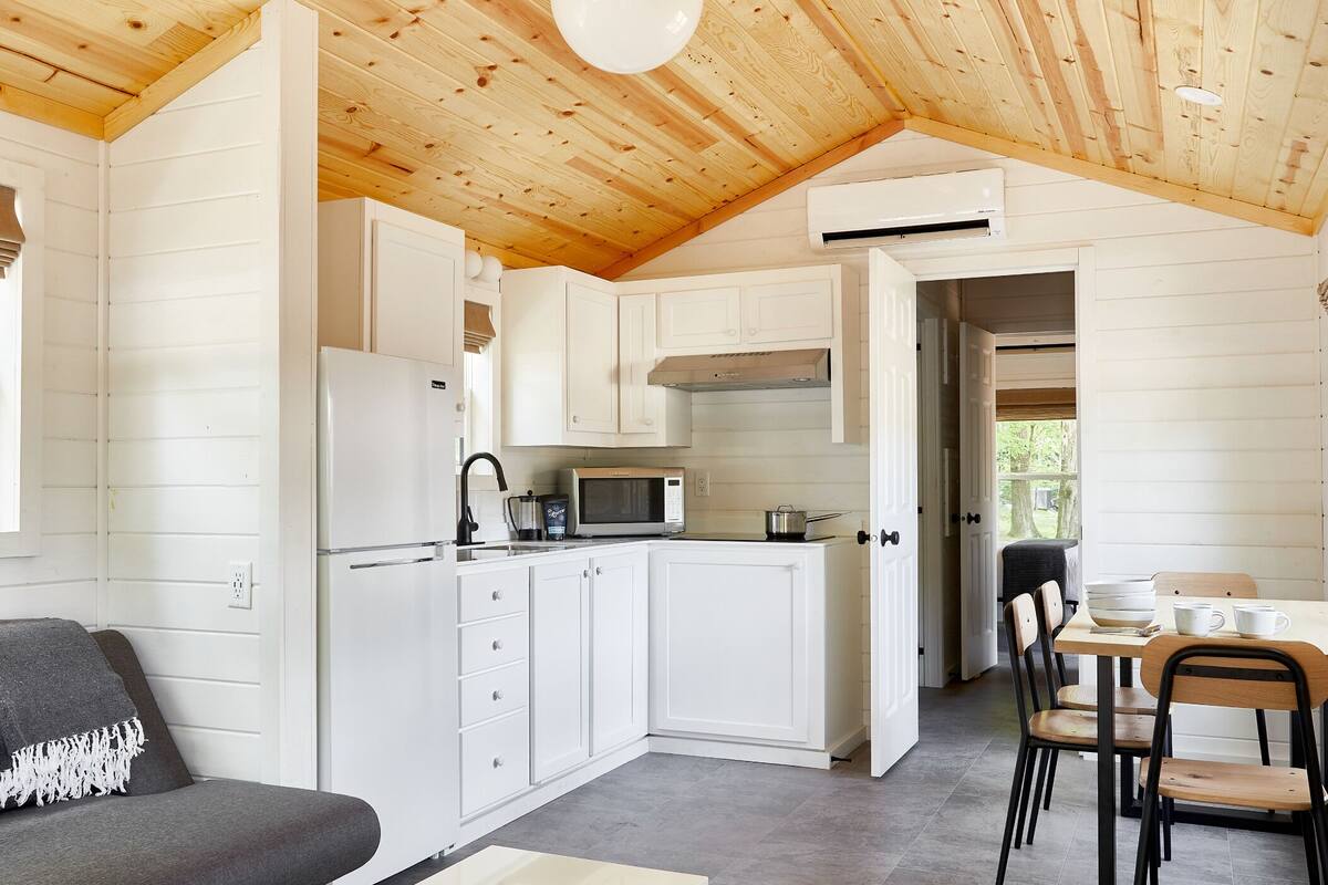 A compact kitchen with white cabinets, a microwave, and a dining area with a table and chairs.