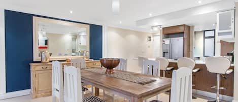 Un comedor moderno con una mesa de madera, sillas blancas y un espejo grande.