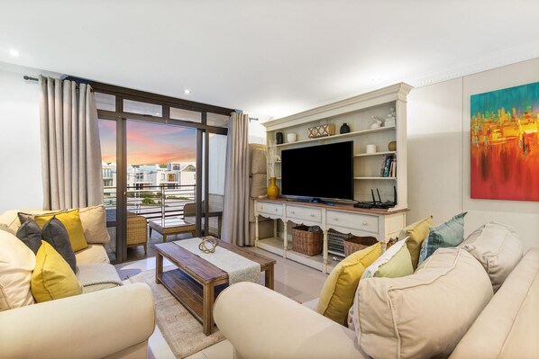 A modern living room with a sofa set, a coffee table, a flat-screen TV, and a fireplace.