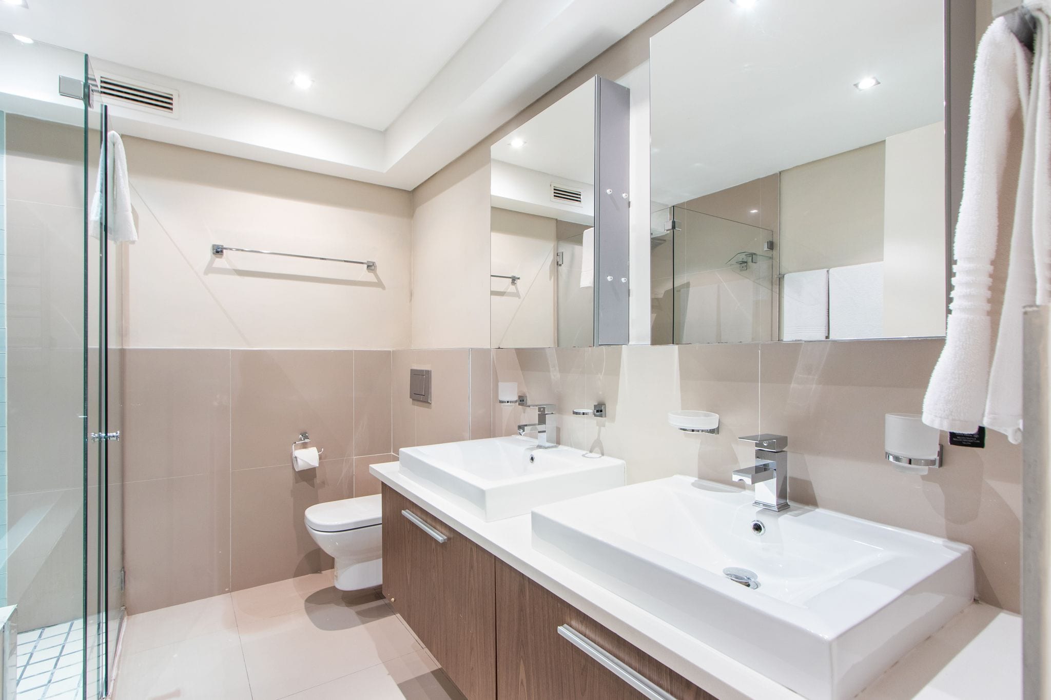 Une salle de bain moderne avec deux lavabos, des toilettes et une douche à l’italienne.