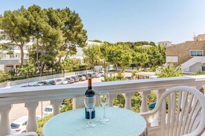 A balcony with a table, two wine glasses, and a bottle of wine.