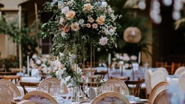 An outdoor dining area with wicker chairs and tables, a floral centerpiece, and a building with balconies in the background. - Hotel Florencia San Miguel (San Miguel)