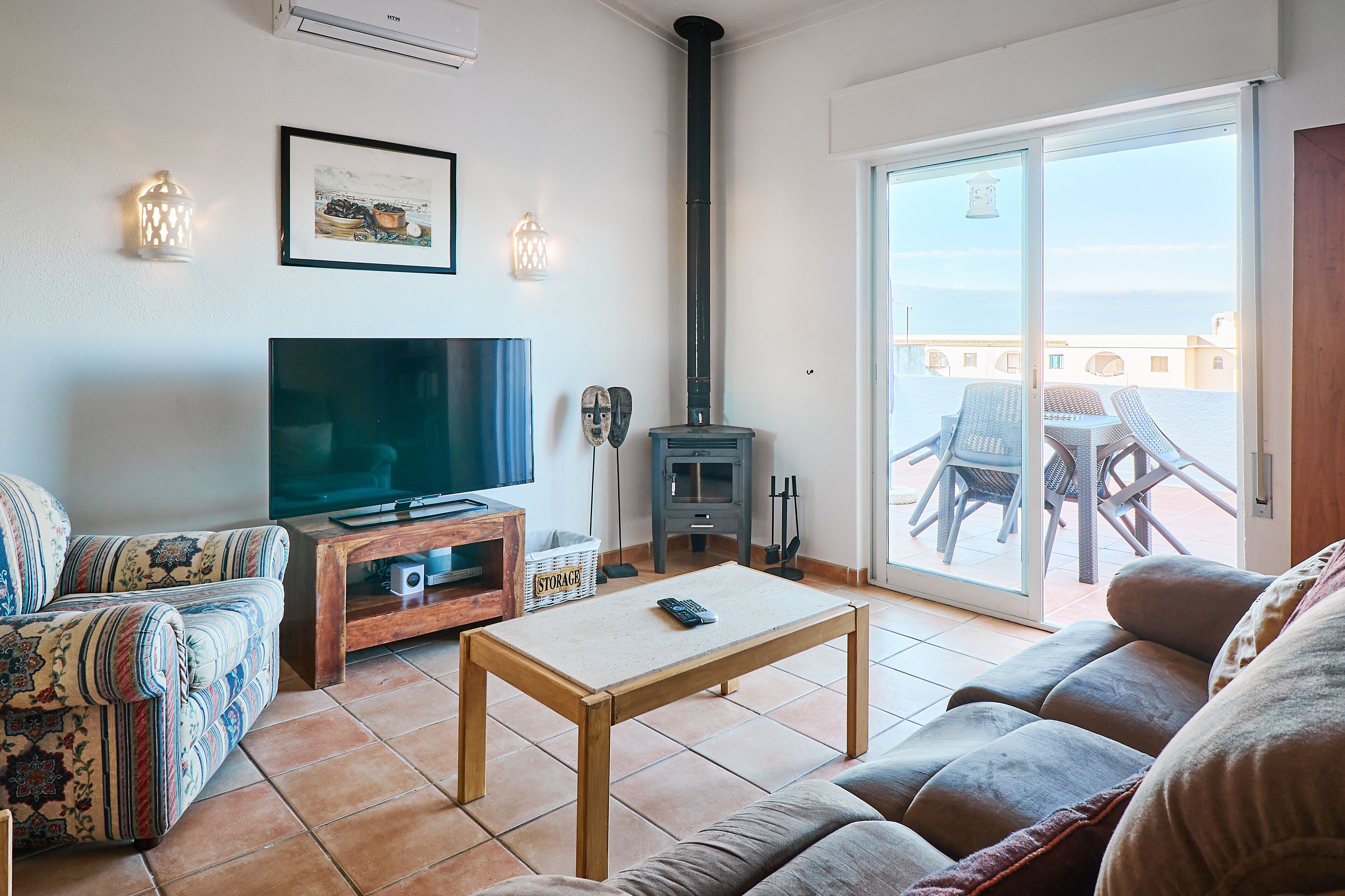 Una sala de estar con televisor, sofá, mesa de centro de madera y chimenea.