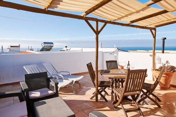 A terrace with a wooden pergola, white walls, and a view of the sea. - Apartment Kornelius (Carvoeiro)