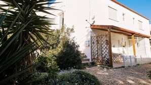 A white building with a tiled roof, a satellite dish, and a wooden fence. - Apartment Kornelius (Carvoeiro)