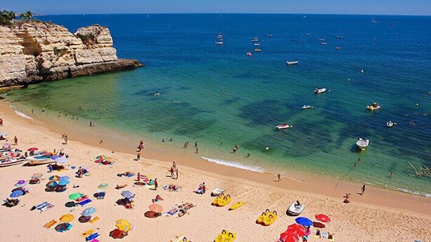 A beach with clear waters, boats, and umbrellas. - Apartment Kornelius (Carvoeiro)