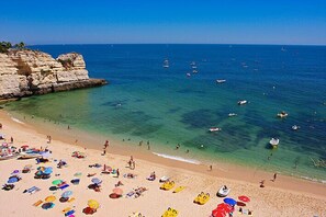 A beach with clear waters, boats, and umbrellas. - Apartment Kornelius (Carvoeiro)