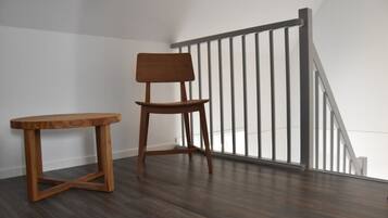 A wooden chair and table in a room with a wooden floor and a white wall.