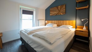 Ein modernes Schlafzimmer mit einem großen Bett, einem Holz-Kopfteil, Nachttischen und einer Wandlampe.