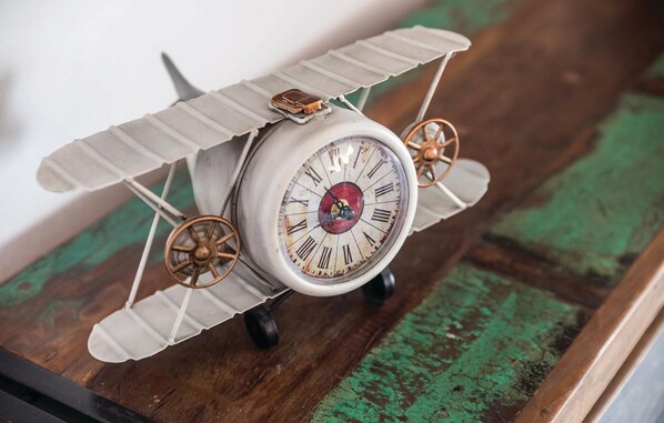 Un reloj de estilo vintage con diseño de avión de hélice, que presenta números romanos y un círculo rojo central.