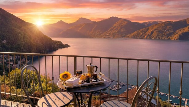 A balcony with a table set for breakfast overlooking a lake and mountains. - Villa Panoramica, Menaggio, Italy (Menaggio)