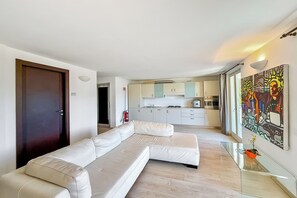 A modern living room with a sectional sofa, a glass coffee table, and a kitchen in the background. - Villa Panoramica, Menaggio, Italy (Menaggio)