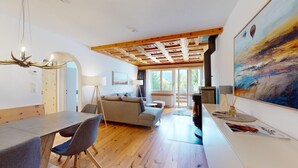 Ein modernes Wohnzimmer mit Holzboden, einem Essbereich mit Tisch und Stühlen und einem großen Gemälde an der Wand.