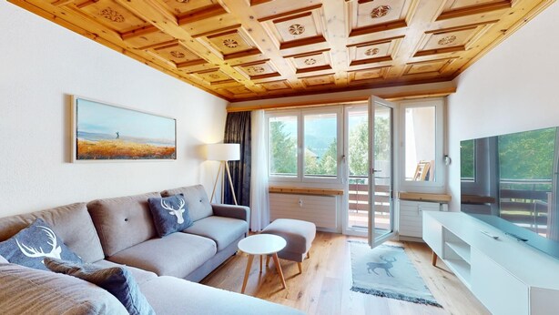 Ein modernes Wohnzimmer mit Holzboden, einer Couch, einem kleinen Tisch und einem Fernseher.