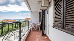 Ein Balkon mit Fliesenboden, einem Stuhl und einem Tisch.