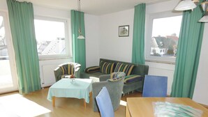 A living room with a sofa, chairs, a table, and a view through a window. - Vacation object Graal Müritz A1 - F01 (Graal-Müritz)