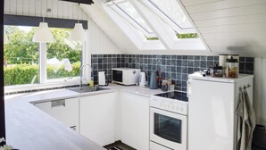 A modern kitchen with skylights, white cabinetry, a microwave, a coffee maker, and a refrigerator. - Lovely home in Storvorde with kitchen (Storvorde)