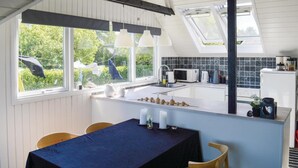 A kitchen with a dining area, featuring a table with a dark tablecloth, chairs, and a view of greenery outside. - Lovely home in Storvorde with kitchen (Storvorde)
