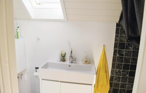 A bathroom with a white sink, a small window, a towel rack, and a bottle of soap.