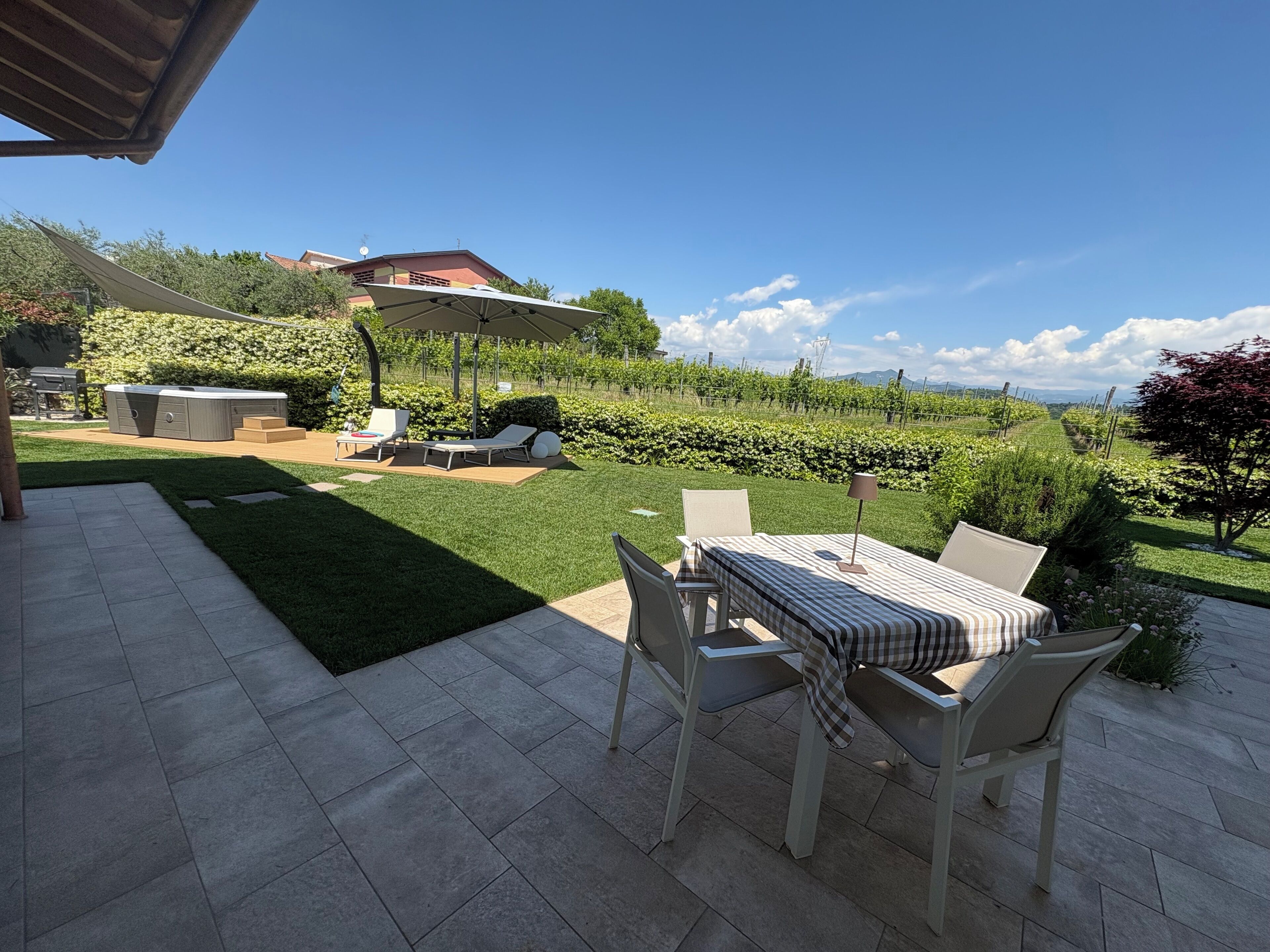 Eine Terrasse mit Tisch und Stühlen, einem Whirlpool und Blick auf einen Weinberg.