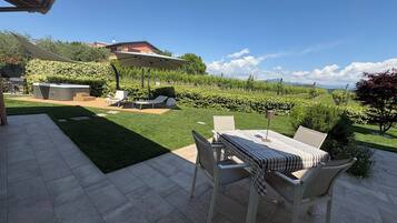 Eine Terrasse mit Tisch und Stühlen, einem Whirlpool und Blick auf einen Weinberg.