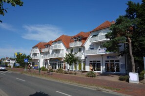 Eine Reihe weißer Gebäude mit roten Dächern, Balkonen und Geschäften.