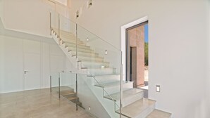 Una escalera moderna con barandillas de vidrio que lleva a una puerta.