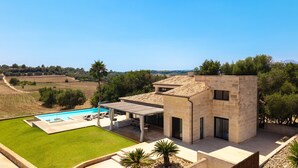 Una villa moderna con piscina, zona de comedor exterior y vistas al campo.