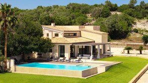 Una villa moderna con piscina, mobiliario de exterior y vistas al bosque circundante.