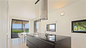 Una cocina moderna con una isla grande, electrodomésticos integrados y amplias ventanas con vistas al exterior.