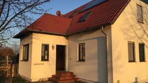 A single-story building with a red-tiled roof, a small entrance with steps, and a sign reading "LEHRINERSTR 5".