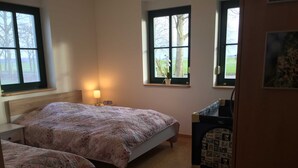 A bedroom with two beds, a nightstand, a lamp, and a dresser with a mirror.