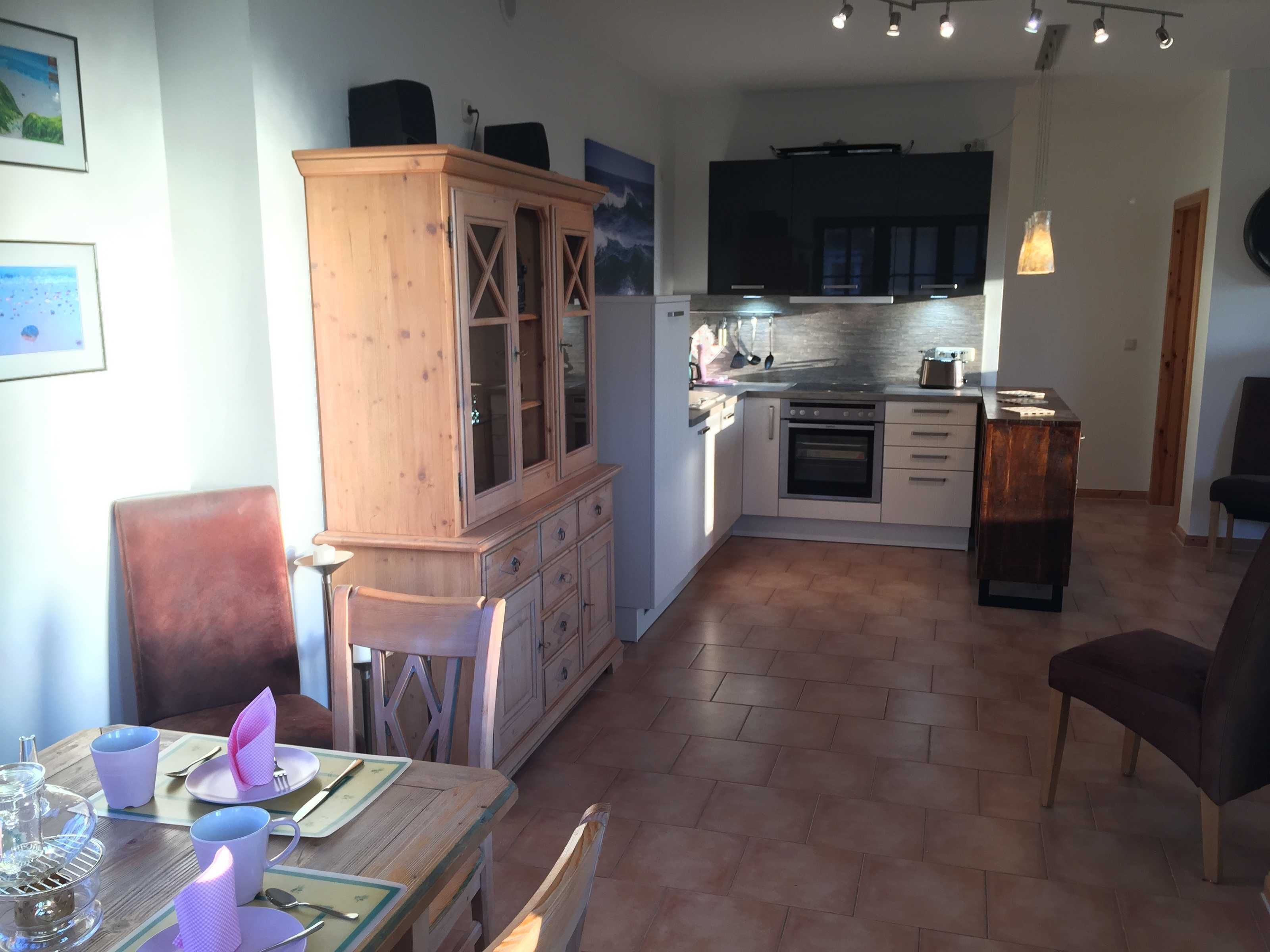 Una cocina compacta con electrodomésticos modernos, un comedor con mobiliario de madera y un pequeño rincón de estar.
