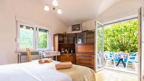 Une chambre avec un lit, une armoire en bois, un radiateur et une table avec des chaises à l’extérieur.