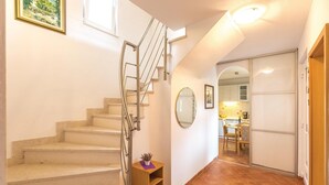 Un escalier avec une rampe en métal mène à un palier. On y trouve une petite table sur laquelle est posée une plante.