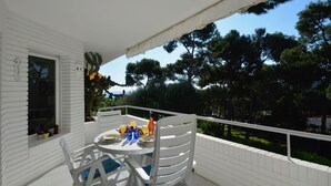A white balcony with a table set for two, surrounded by white railings and a view of trees. - Holiday rental apartment with swimming pool in Begur, Aiguablava (Begur)
