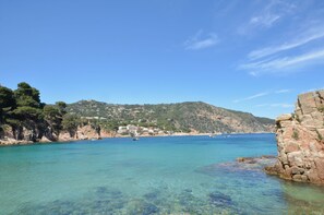 Un paysage côtier caractérisé par des eaux limpides, des falaises rocheuses et des bâtiments construits sur une colline.
