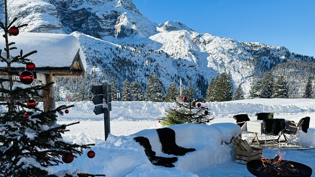 A snow-covered outdoor area with a wooden deck, a fire pit, and a Christmas tree. - Private apartment in the Dolomites: 2-8 persons (St. Lorenzen)