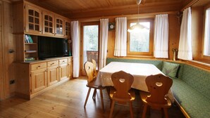 A wooden cabin interior with a dining table, chairs, a television, and a sofa. - Private apartment in the Dolomites: 2-8 persons (St. Lorenzen)