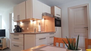 Une cuisine moderne avec des meubles en bois, un four encastré et un coin repas comprenant une table et des chaises.