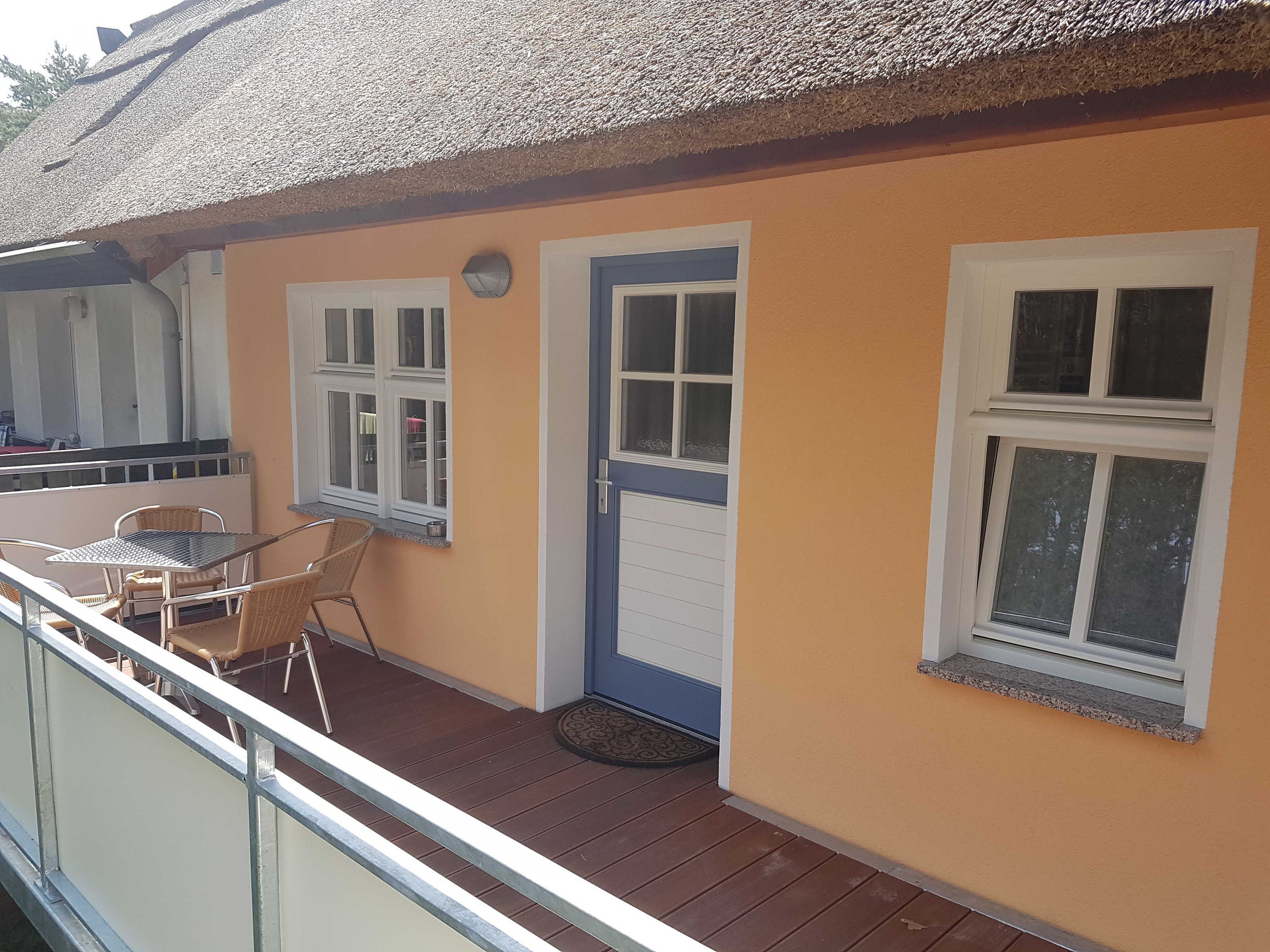 Ein Balkon mit Korbmöbeln, einer Tür und Fenstern.
