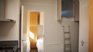 A compact kitchen with a stove, a white radiator, and a wooden wardrobe. - Six-person Veluwe Lounge (Voorthuizen)