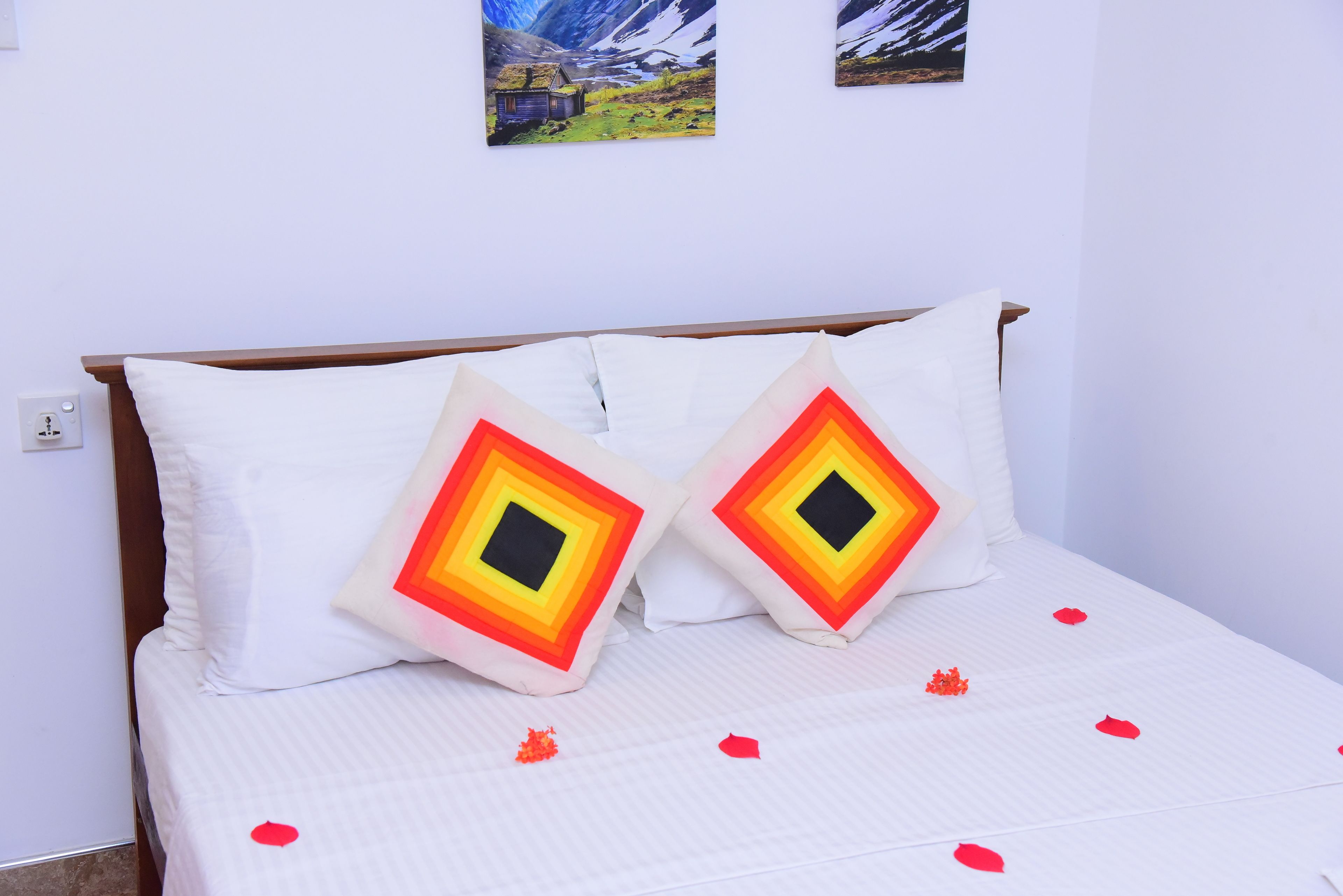 A bed with white bedding and two pillows with a geometric pattern.