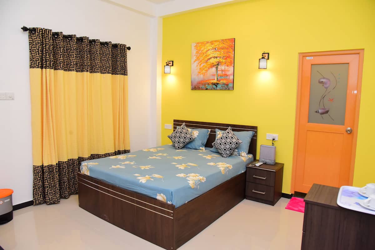 A bedroom with a bed, bedside tables, a nightstand, a painting, and a door.