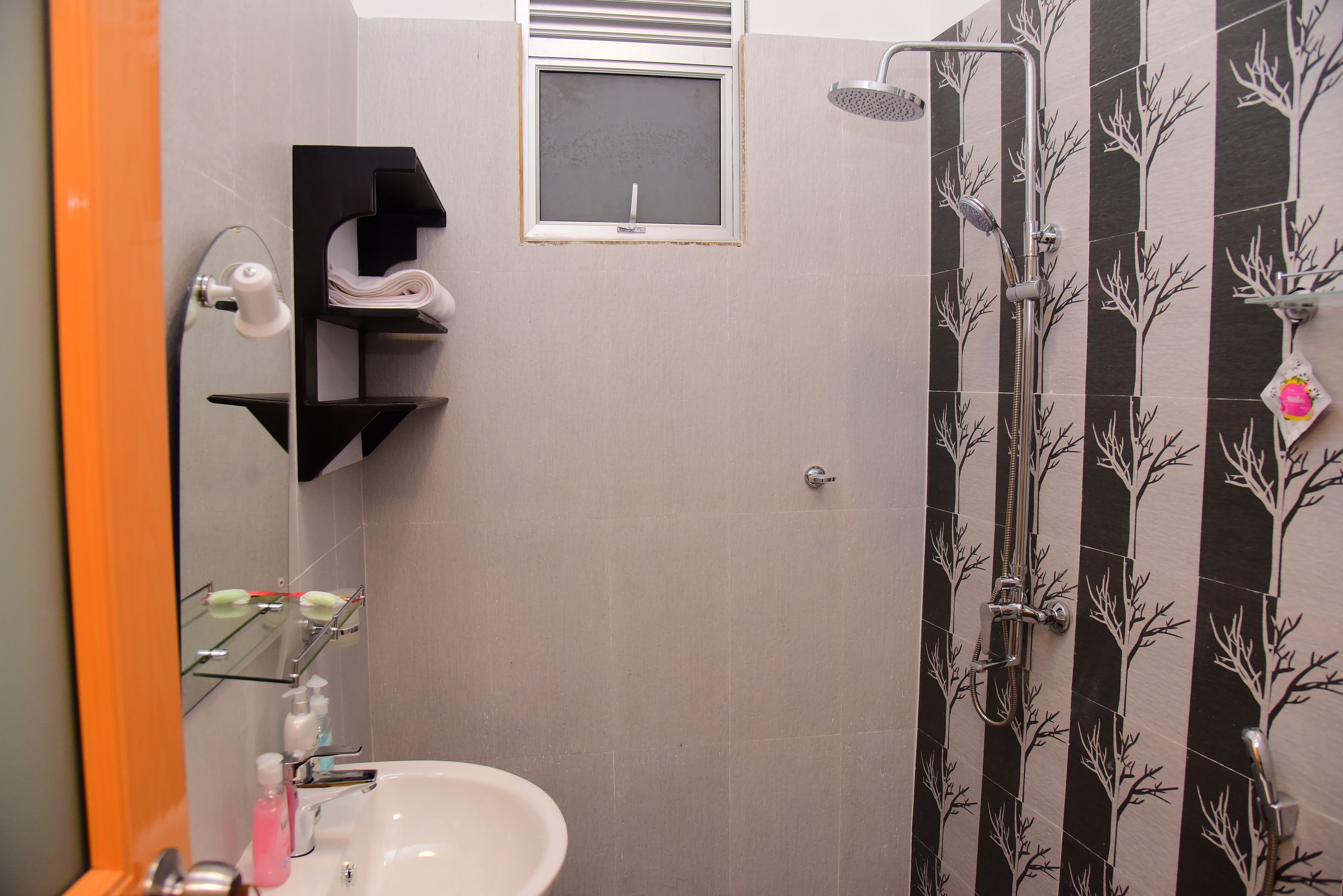 Un baño con lavamanos, espejo, toallero, ducha y azulejos decorativos.