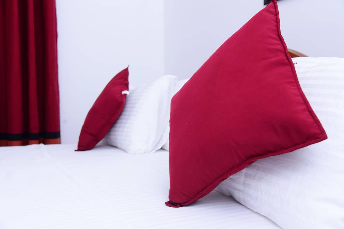 A bed with white bedding and red pillows.